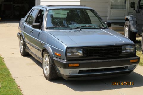 1985 Volkswagen GTI - This 1985 Volkswagen Jetta is seen from a 3q front angle, parked next to another vehicle.