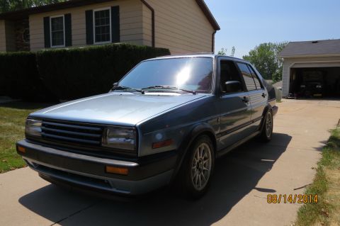 1985 Volkswagen GTI - Silver 1985 Volkswagen Jetta sedan parked in a driveway with a house and garage in the background.