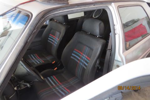 1985 Volkswagen GTI - The interior of a car features distinctive plaid fabric on the seats and headrests, with a sunroof visible above.