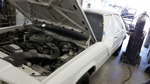 1991 Ford LTD Crown Victoria - A white sedan is shown with its hood open, revealing the engine bay, and parts of the body are covered in plastic sheeting.