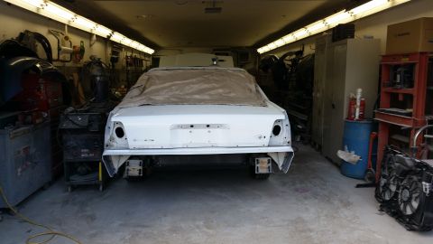 1991 Ford LTD Crown Victoria - A white sedan is parked in a garage with tools and equipment around it.