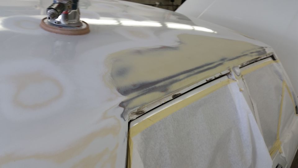 Car body panel with sanding marks and masking tape, undergoing repair