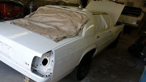1991 Ford LTD Crown Victoria - A white sedan is being worked on in a garage, with another vehicle visible in the background.