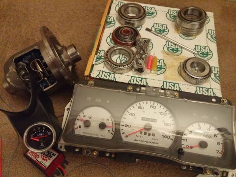 2000 Mercury Grand Marquis - Various automotive parts are laid out, including a differential, several bearings, an MSD ignition box, and a Marauder instrument cluster.