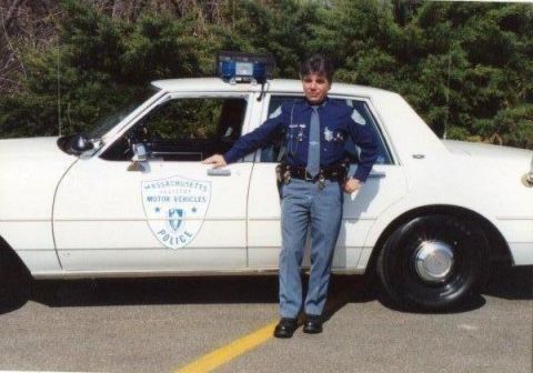 1991 Ford LTD Crown Victoria - Massachusetts police officer stands next to a white 1991 Ford Crown Victoria LTD police car with a flat rear tire.