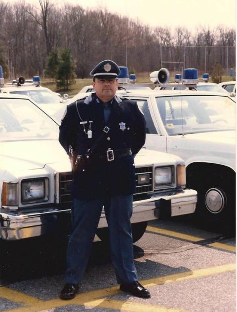 1991 Ford LTD Crown Victoria - A police officer stands in front of a line of marked patrol vehicles.