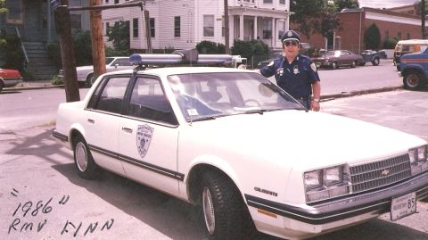 1991 Ford LTD Crown Victoria - A Massachusetts Registry of Motor Vehicles police car is shown with an officer. The car is a 1986 Chevrolet Caprice.