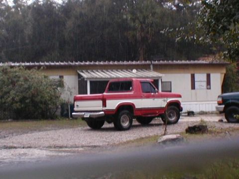 1979 Ford Bronco II - This red and white Ford Bronco is parked next to a mobile home, with a dark SUV visible on the right.