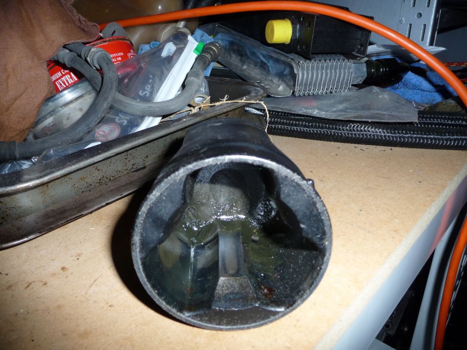 Close-up of a greasy automotive part, possibly a CV joint, with a red can labeled "EXTRA" in the background