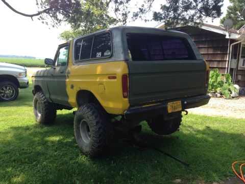 1979 Ford Bronco - This lifted Ford Bronco has a two-tone paint scheme and is parked next to a silver pickup truck.