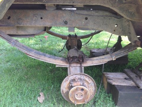 1979 Ford Bronco - Close-up view of a vehicle's rear axle and leaf spring suspension system, showing signs of rust and wear.