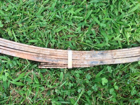 1979 Ford Bronco - Leaf spring part resting on grass, showing signs of rust and wear.