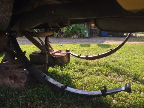 1979 Ford Bronco - Leaf springs and undercarriage components are visible, supported by jack stands.