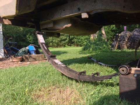 1979 Ford Bronco - Close-up of a vehicle's leaf spring suspension system, with a fuel tank overhead.