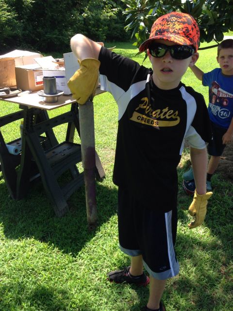 1979 Ford Bronco - A young boy in a Pirates shirt and camouflage hat holds a shock absorber while standing in a yard with a table of parts nearby.