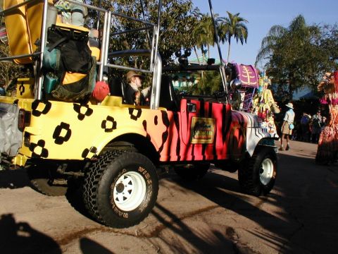 1979 Ford Bronco II - This customized jeep features a vibrant animal print paint scheme and is loaded with luggage, suggesting it's part of a safari or parade.