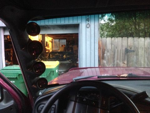 1992 Ford F-150 - A gauge pillar with four gauges is mounted inside a vehicle, with a garage and fence visible through the windshield.
