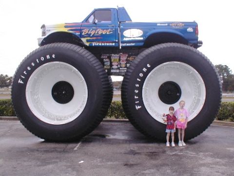 1979 Ford Bronco II - Monster truck Bigfoot with enormous tires, dwarfing two children standing nearby.
