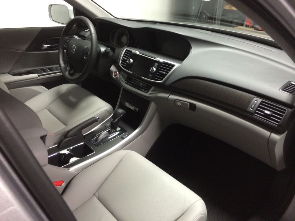 Car interior with light gray leather seats, dashboard, steering wheel, and center console. Wood trim accents visible