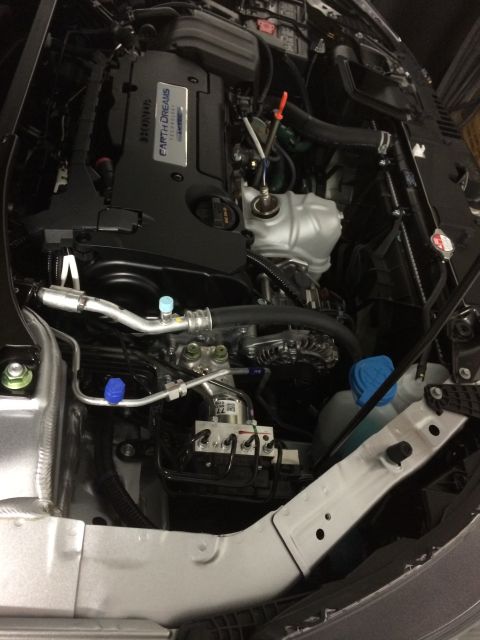 2014 Honda Accord - The engine bay of a 2014 Honda Accord is visible, the 'Earth Dreams Technology' engine cover.