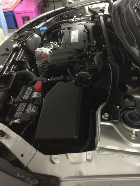 2014 Honda Accord - The engine bay of a silver Honda Accord, showing the engine, battery, and various components.