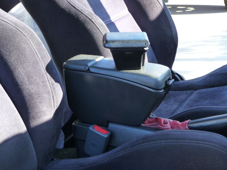 Black center console armrest with red cloth tucked underneath, viewed from passenger seat