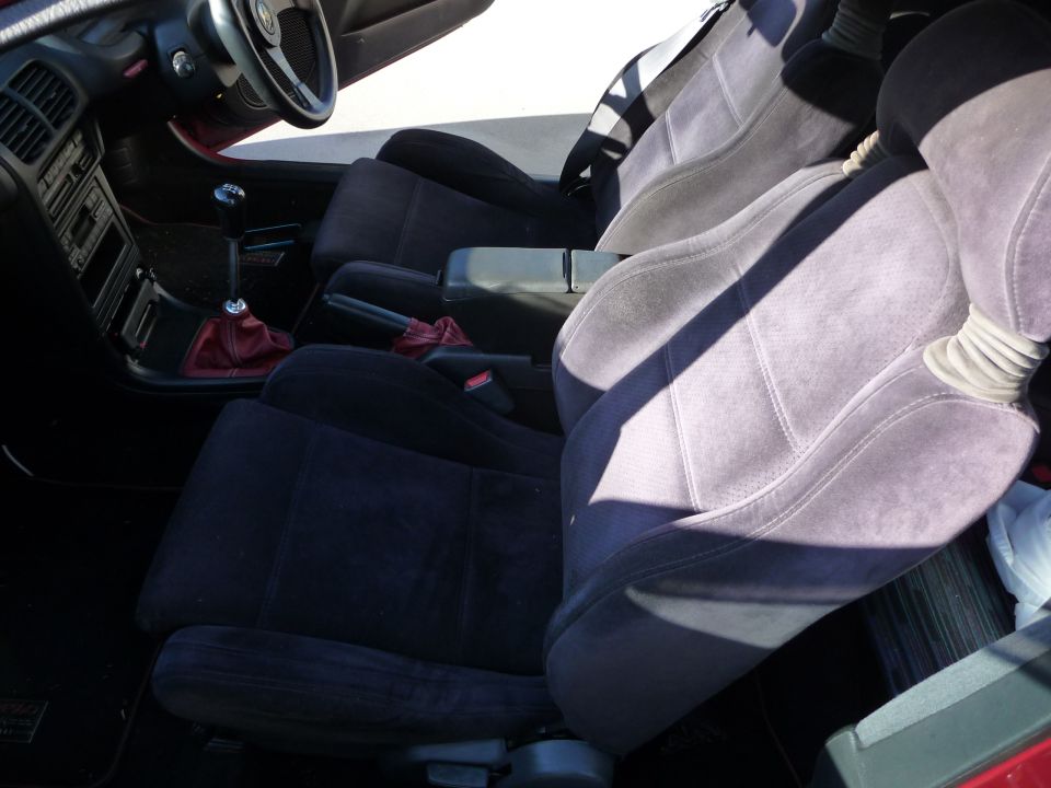 Interior view of car seats and dashboard with red shifter boot