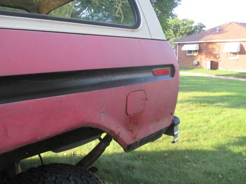 1979 Ford Bronco - The rear quarter panel of a red 1979 Ford Bronco shows its distinctive black trim and fuel door.