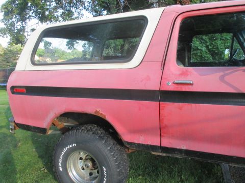 1979 Ford Bronco - Side view of a red and white 1979 Ford Bronco, showing its distinctive body style and BFGoodrich tires.