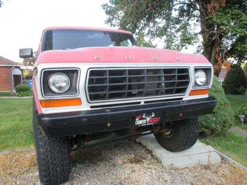 1979 Ford Bronco - The front grille and headlights of a classic Ford Bronco are visible, parked on concrete blocks.