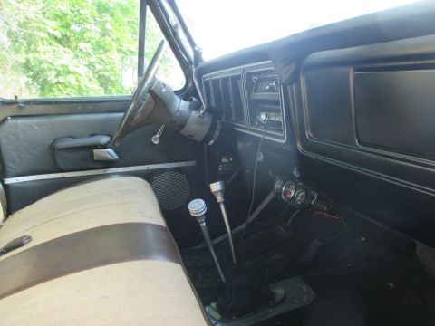 1979 Ford Bronco - The interior of a 1979 Ford Bronco features a bench seat and dual floor shifters.