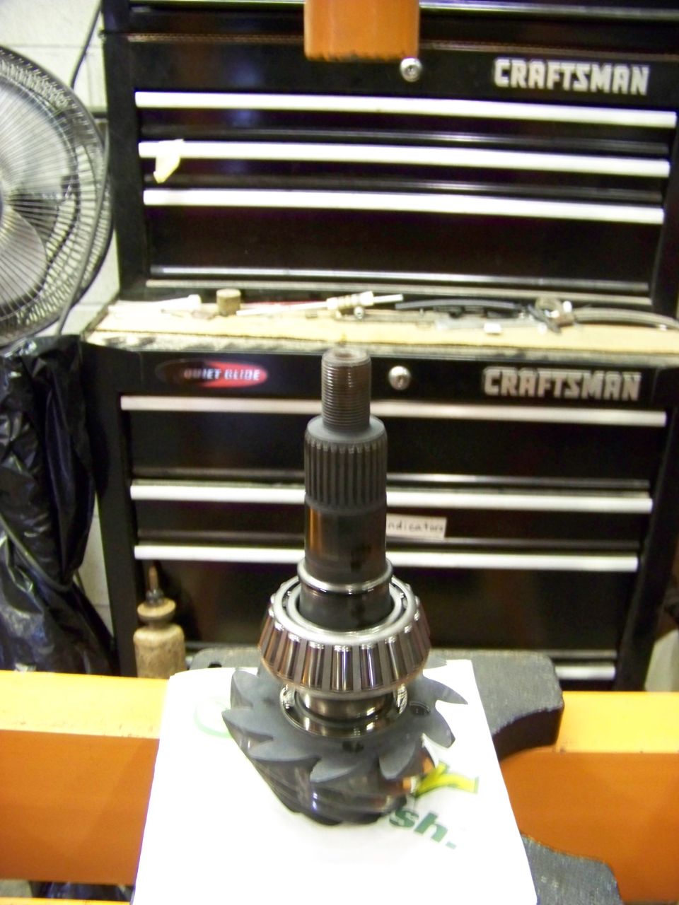 Differential pinion gear with bearing and splined shaft, in front of a Craftsman tool chest