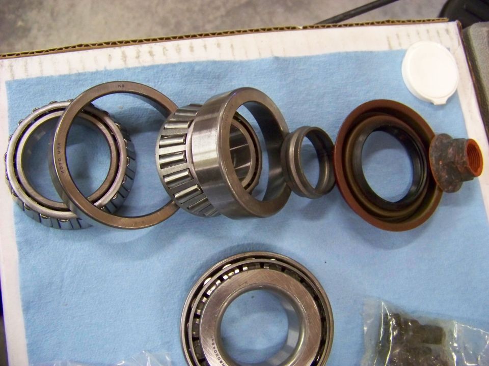 Differential bearings and seal laid out on a blue cloth. Includes tapered roller bearings, races, and a rubber seal
