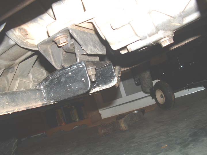 Underside view of transmission mount bolted to crossmember on a lifted vehicle