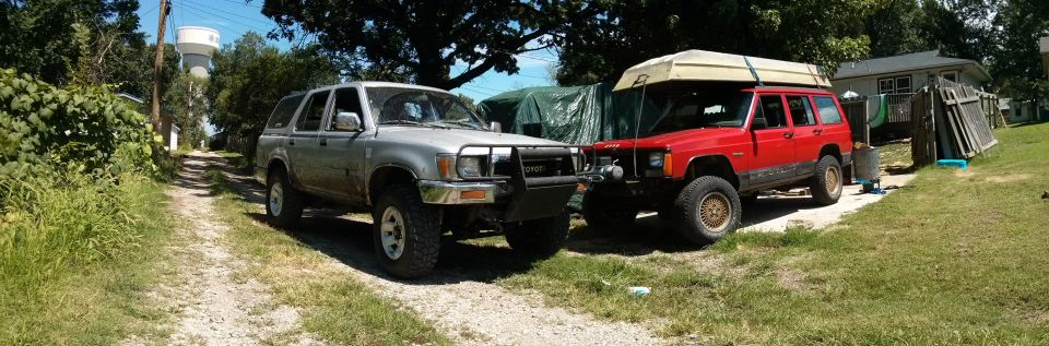 Silver Toyota 4Runner and red Jeep Cherokee parked side-by-side on a gravel driveway