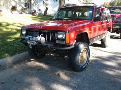1986 Ford Bronco - This red Jeep Cherokee XJ features an aftermarket bumper and winch, along with gold mesh wheels.