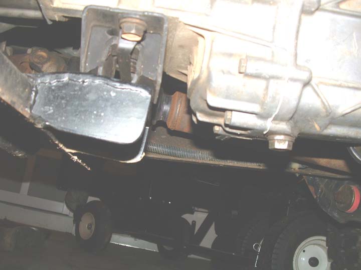 Welded transmission crossmember mount bracket under a truck next to the aluminum tailshaft