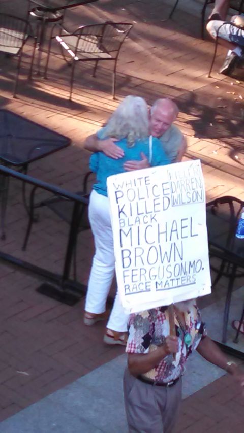 1971 Ford Ranchero - A protest sign about racial matters is held by a person embracing another individual.