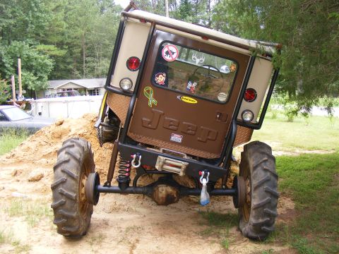 Modified Jeep CJ-7 with large tires, lifted suspension, and custom roll cage. The rear door has 'JEEP' letteri