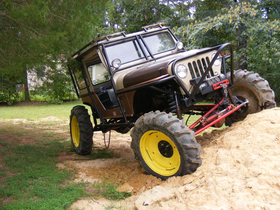 Custom jeep with big tires and roll cage on a dirt mound
