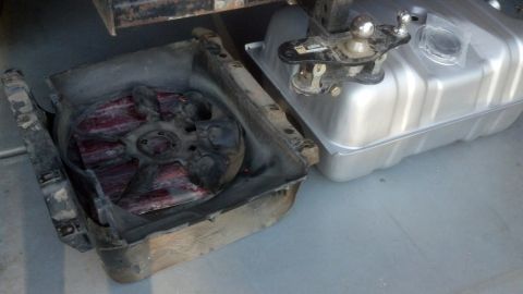 1995 Ford Bronco - A detached radiator fan shroud sits next to a silver fuel tank and hitch receiver.