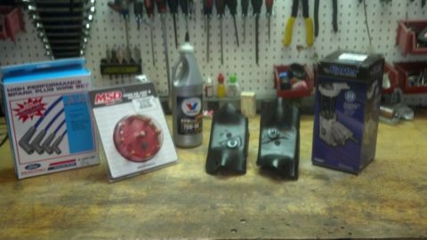 1995 Ford Bronco - Automotive parts including spark plug wires, distributor cap, oil, and ignition coils are laid out on a workbench.