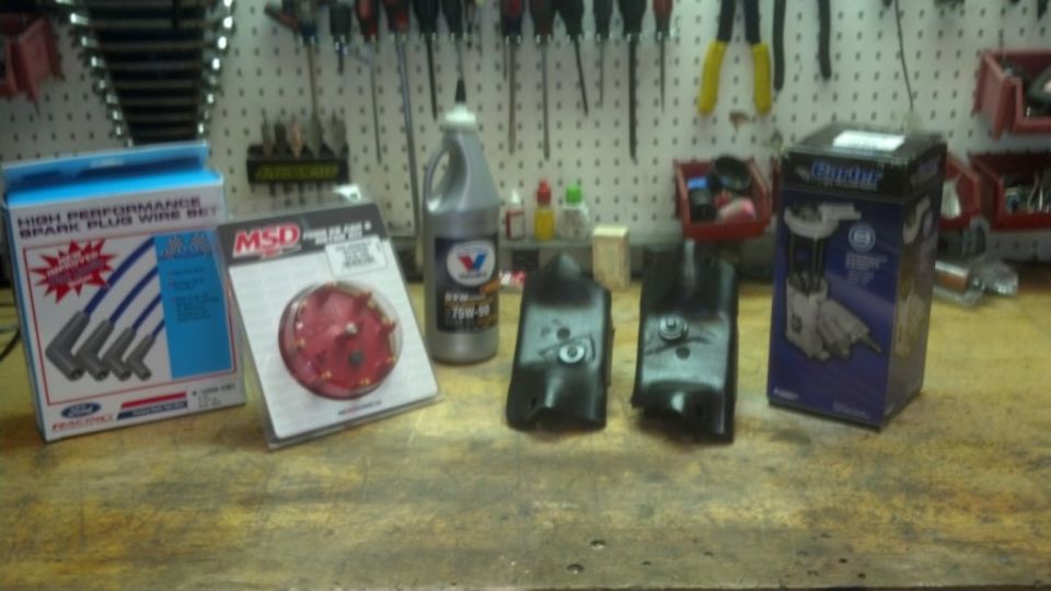 Ford spark plug wire set box, MSD distributor cap, Valvoline oil bottle, and two ignition coils on a workbench