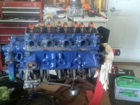 1978 Ford Bronco - V8 engine block painted blue, with orange valve covers, resting on an engine stand.
