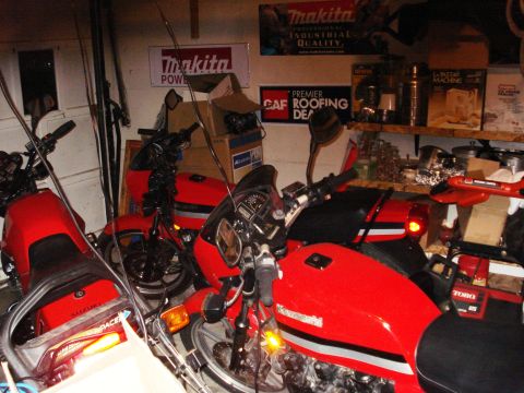 2008 Ford Crown Victoria - Multiple red motorcycles are stored in a garage, surrounded by various tools and supplies.
