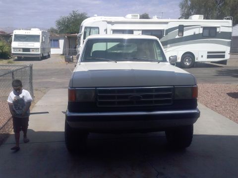 1988 Ford Bronco - This 1988 Ford Bronco is parked in front of two RVs, with a child walking nearby.