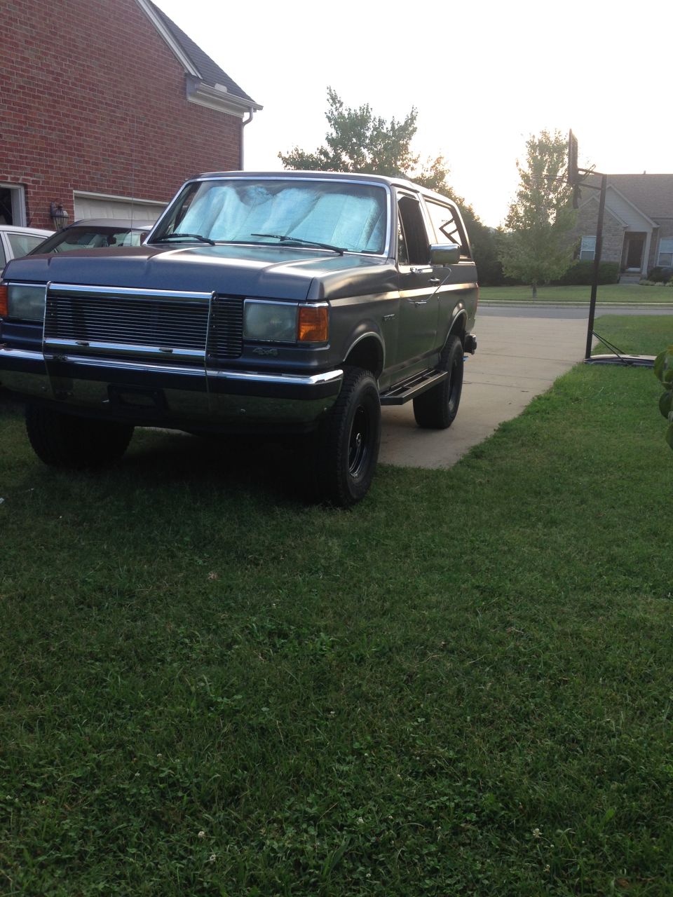 Dark blue Ford Bronco parked in a driveway, front quarter view