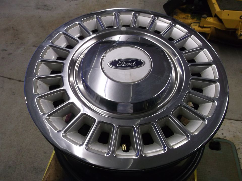 Chrome and silver Ford hubcap with rectangular cutouts and a central Ford logo