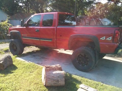 1986 Ford Bronco - A red pickup truck with a lifted suspension and off-road tires is parked outdoors.