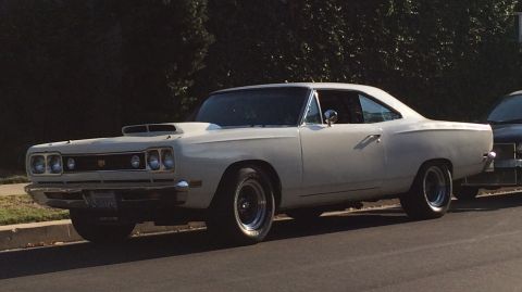 1968 Ford Mustang - A white 1969 Dodge Super Bee is parked curbside, a prominent hood scoop and classic muscle car lines.